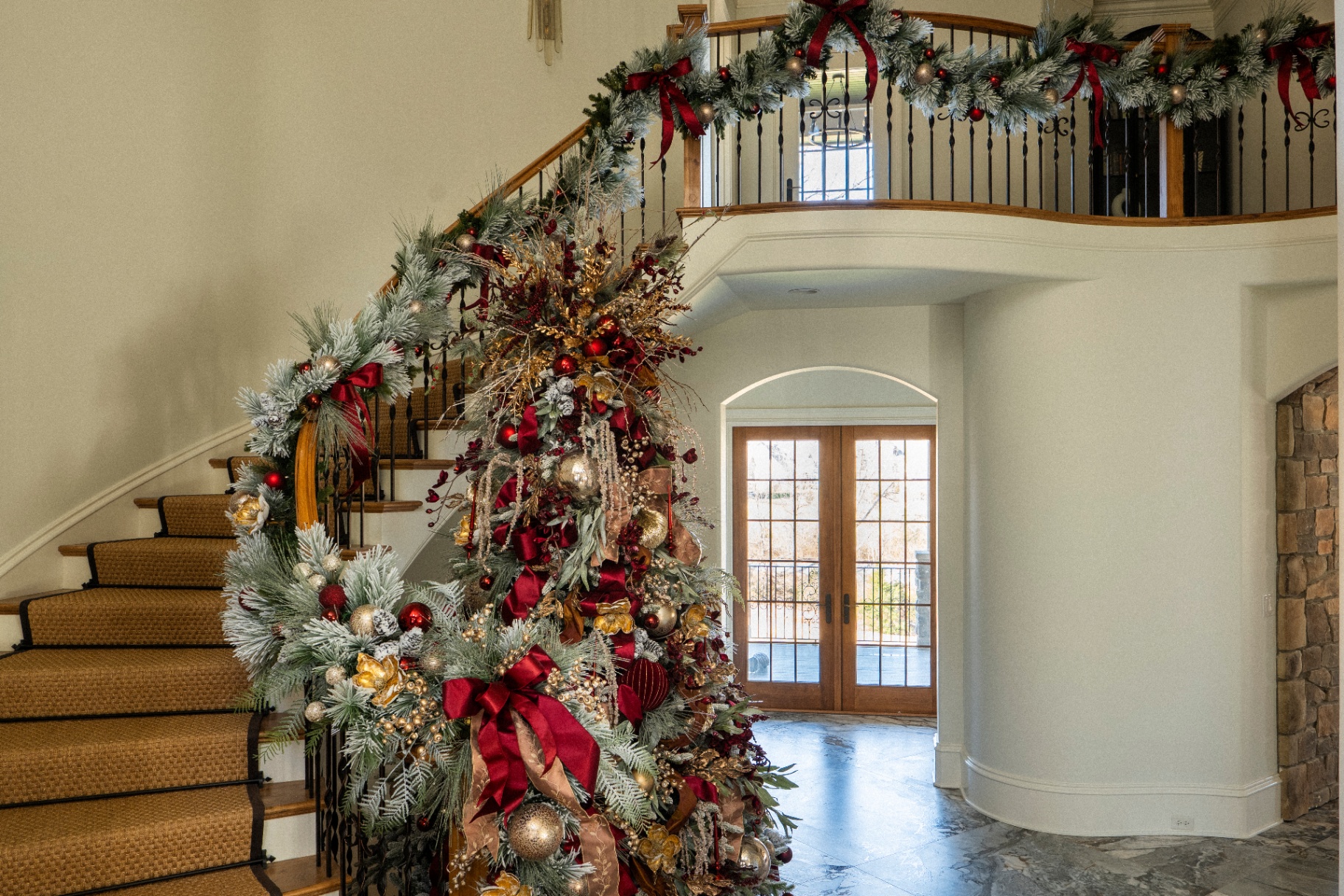 Crimson and gold flocked Christmas tree and garlanded staircase in a Knoxville foyer